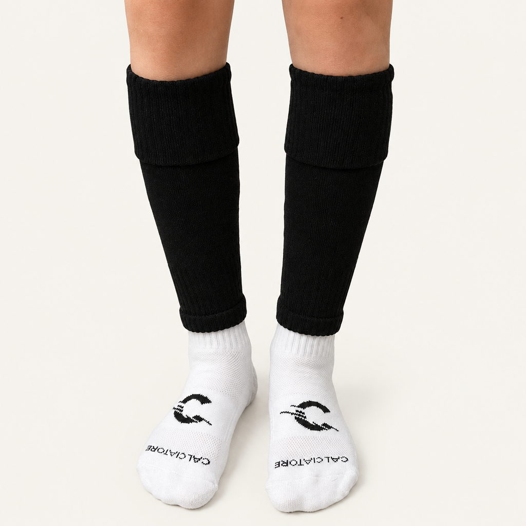 Black football sock sleeves worn with white socks on a neutral background
