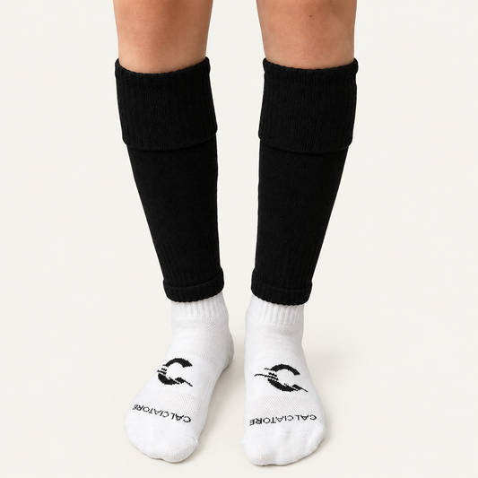 Black football sock sleeves worn with white socks on a neutral background